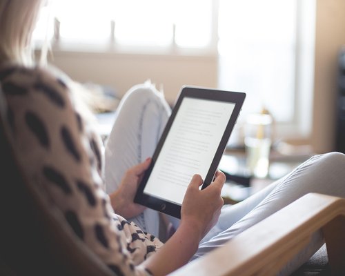 Mature woman enjoying reading a tablet in a bright living room
